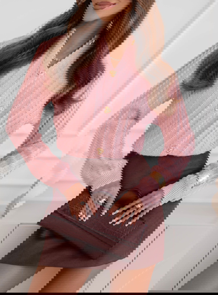 Pudrowy sweter zapinany na guziki...